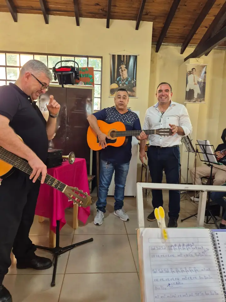 Estudiantes de música en un salón moderno practicando con instrumentos de cuerda y viento.